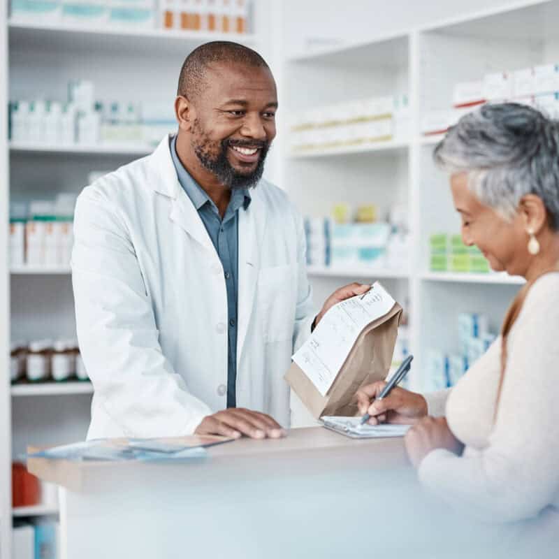 Pharmacist helping patient at pharmacy counter.